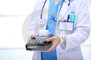 Doctor is holding payment terminal in hands. Paying for health care. Doctor