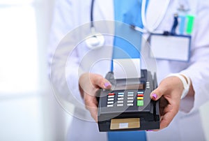 Doctor is holding payment terminal in hands. Paying for health care. Doctor