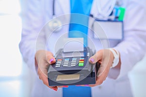 Doctor is holding payment terminal in hands. Paying for health care. Doctor