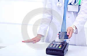 Doctor is holding payment terminal in hands. Paying for health care. Doctor