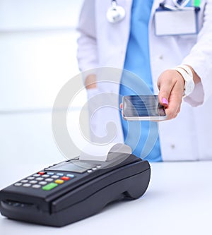 Doctor is holding payment terminal in hands. Paying for health care. Doctor