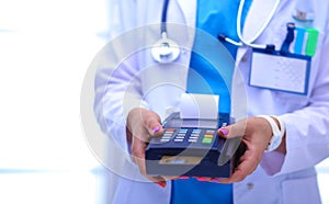 Doctor is holding payment terminal in hands. Paying for health care. Doctor