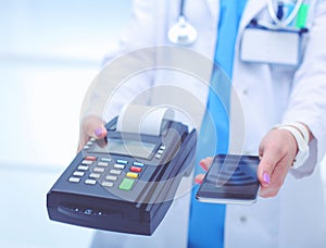 Doctor is holding payment terminal in hands. Paying for health care. Doctor