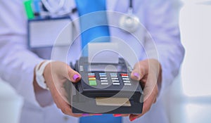 Doctor is holding payment terminal in hands. Paying for health care. Doctor