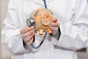 Doctor holding piggy bank close up. Medical insurance and health care money concept