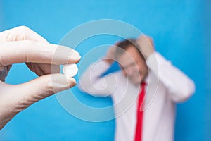 The doctor is holding a pill for psychosis, in the background is a man who has a mental disorder, psychosis