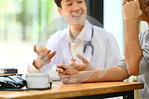 Doctor holding pills bottles explaining medication treatment to senior patient. Medicine and health care service concept