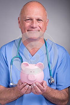 Doctor holding a pink piggy bank, wearing surgical mask and stethoscope.