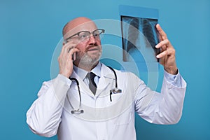 Doctor holding an x-ray of the chest talking on phone with patient