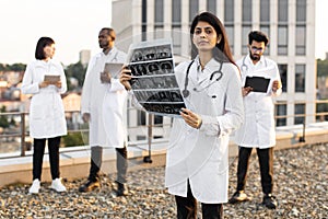 Doctor holding x-ray scan of patient during break outdoors hospital.