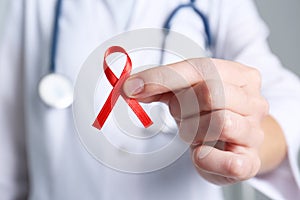 Doctor holding red awareness ribbon, closeup. World AIDS disease day