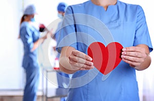 Doctor holding red heart at hospital, closeup