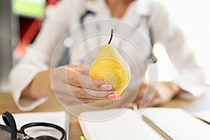 Doctor holding ripe yellow pear in hand