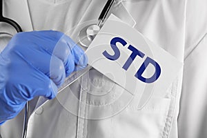 Doctor holding sheet of paper with abbreviation STD, closeup