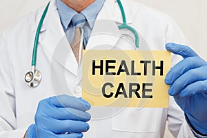 Doctor holding sign with text HEALTH CARE closeup