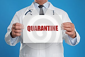 Doctor holding sign with text QUARANTINE on background, closeup. Stay at home during coronavirus outbreak