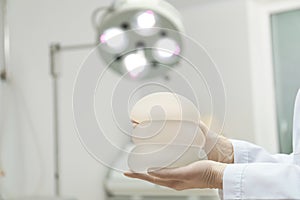 Doctor holding silicone implants for breast augmentation in clinic, space for text.