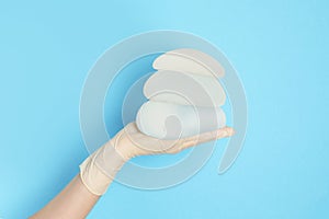 Doctor holding silicone implants for breast augmentation on color background, space for text.