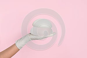 Doctor holding silicone implants for breast augmentation on color background, space for text.