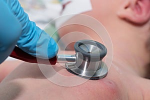 Doctor holding stethoscope in his hand and doing auscultation newborn baby in neonata photo