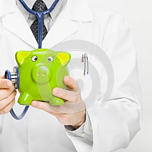 Doctor holding stethoscope and piggybank