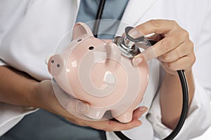 Doctor Holding Stethoscope to Piggy Bank