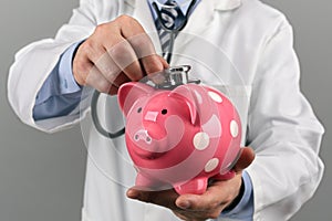 Doctor holding stethoscope to piggy bank