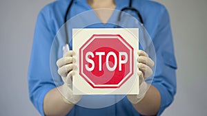 Doctor holding stop sign, warning about unhealthy lifestyle, harmful habits