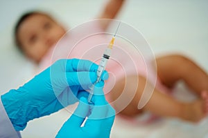 doctor holding syringe and preparing vaccine giving injection to baby