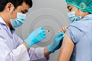 Doctor holding syringe and using cotton before make injection to nurse or Medical professionals in mask. Covid-19 or coronavirus