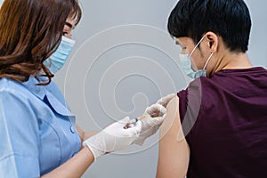Doctor holding syringe and using cotton before make injection to patient in medical mask. Covid-19 or coronavirus vaccine