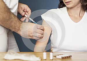 Doctor holding a syringe and vaccinating a woman a