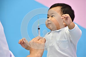 Doctor holding syringe with vaccine for Asian baby
