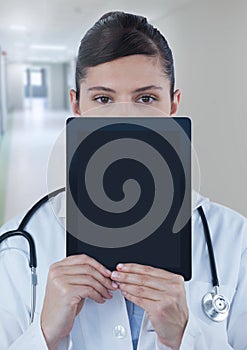 Doctor holding tablet over face in corridor