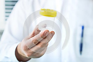 Doctor holding urine sample cup. Medical test in hospital.