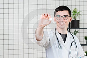 Doctor holding white pill, close-up. Concept of pharmacist, drugs, diet pill, antibiotics or vitamins