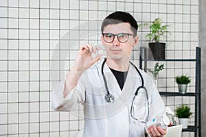 Doctor holding white pill, close-up. Concept of pharmacist, drugs, diet pill, antibiotics or vitamins