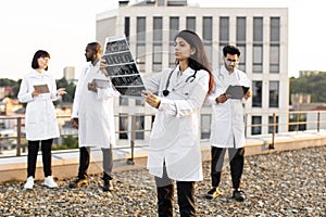 Doctor holding x-ray scan of patient during break outdoors hospital.