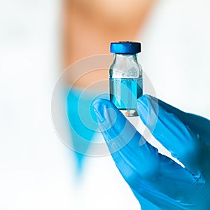 Doctor Holds a Blue Medical Fluid in an Ampule