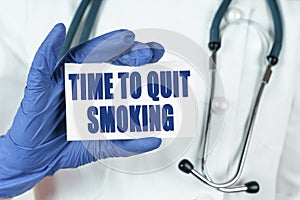 The doctor holds a business card that says - TIME TO QUIT SMOKING