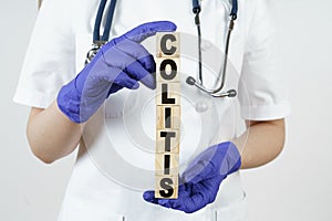 The doctor holds cubes in his hands on which it is written - COLITIS