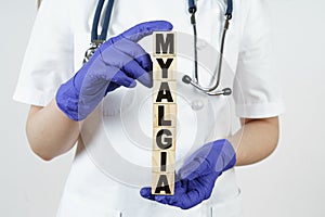 The doctor holds cubes in his hands on which it is written - MYALGIA