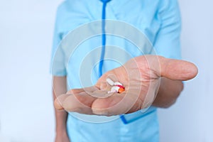 doctor holds drugs in hand, close-up medicinal capsules, pills, vitamins in male palm, ensuring delivery of proper medication and