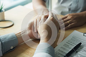 Doctor holds hands and leaves comforting counselors to patient photo