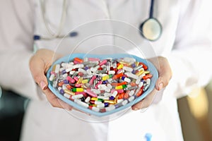Doctor holds heart-shaped plate with colorful pills in hands