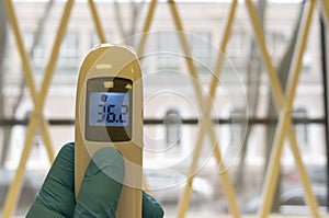 The doctor holds the infrared non-contact thermometer. The digital device displays the normal body temperature in degrees Celsius