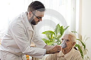 The doctor holds inhaler the face of an old woman.