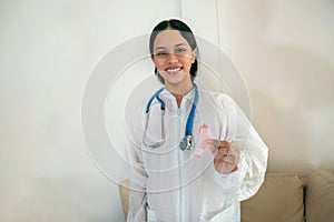 Doctor holds a pink ribbon for breast cancer awareness. Fuzzy background