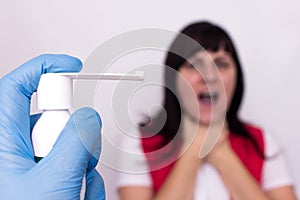 Doctor holds spray medicine for sore throat, in the background a girl who has throat sore throat and sore throat, infection