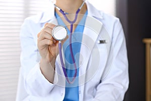 Doctor holds stethoscope head, closeup. Physician ready to examine and help patient. Medical help and insurance in